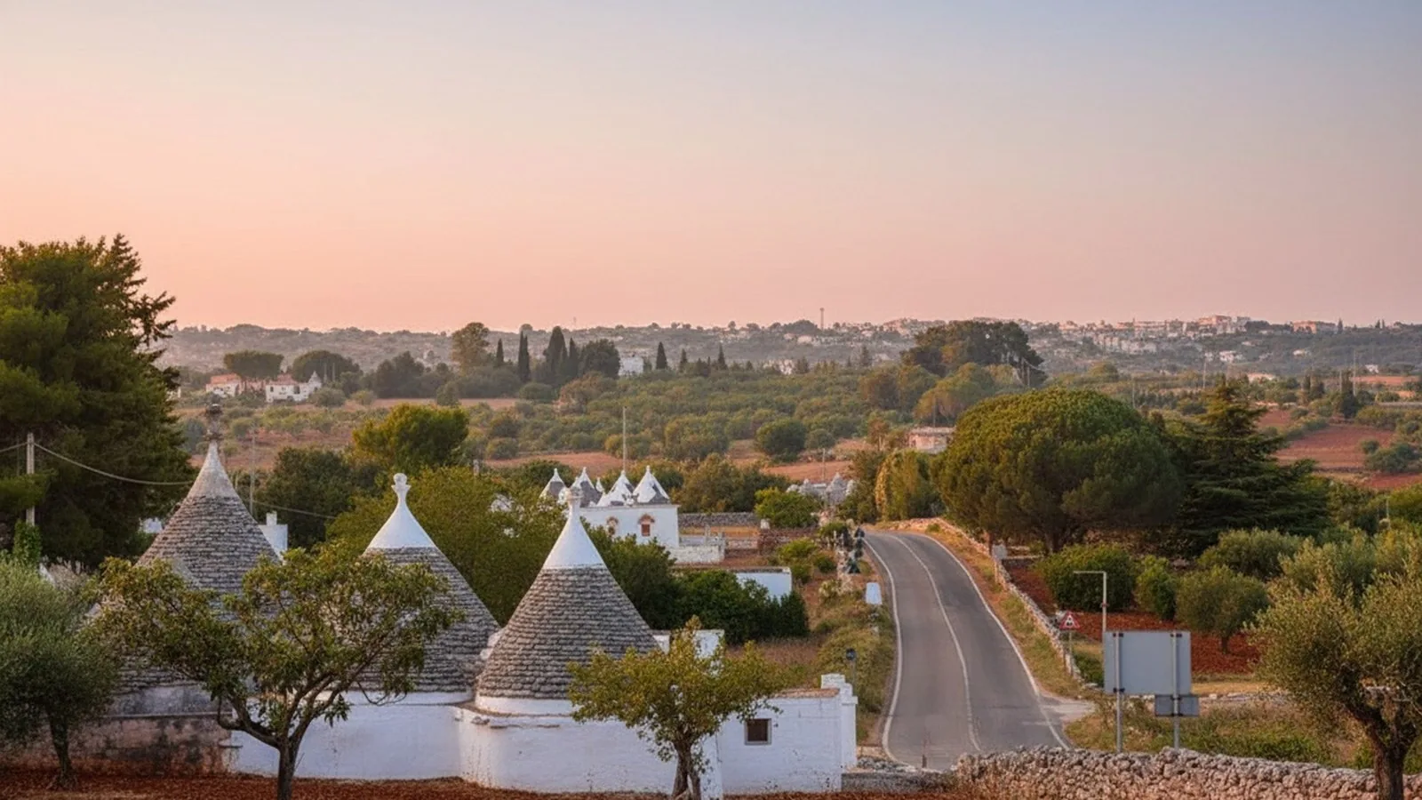 Una strada di campagna fra i trulli della Valle d'Itria al tramonto